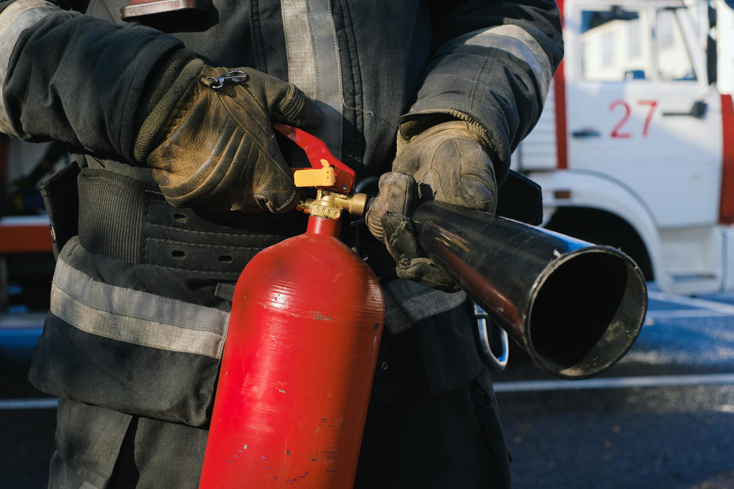 Firefighter in uniform holding a fire extinguisher, emphasizing safety and emergency readiness.